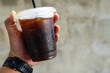 © Dontree - The hand holding a cold black coffee in plastic cup.