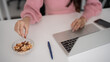 © Pichsakul - Adult Asian woman hands pick healthy snack nuts work laptop home office remote productivity well being