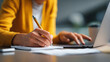 © Atchariya63 - Handwriting notebook laptop office workspace woman writing notes while using computer