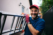 © Drazen - Happy worker carrying ladder and looking at camera.