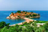 picturesque seascape of beautiful isle Sveti Stefan near Budva Montenegro. Scenic orange buildings in Ardiatic sea with blue water and amazing sky on background of landscape