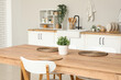 © Pixel-Shot - Wooden dining table with houseplant and wicker mats in stylish kitchen