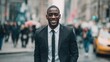 © pinkrabbit - portrait of a handsome smiling young businessman boss in a black suit walking on a city street to his company office. blurry street background, confident