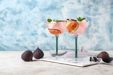 Wall Mural - Glasses of tasty fig lemonade with mint and fruits on white table