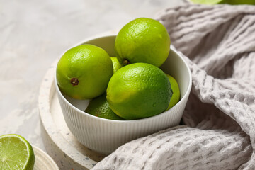 Wall Mural - Bowl with fresh ripe limes on grey background, closeup