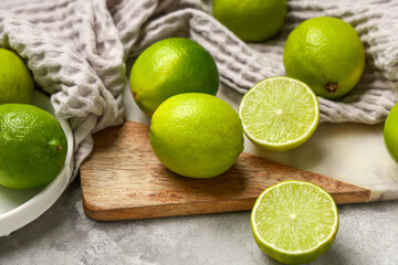 Wall Mural - Cutting board with fresh ripe limes on grey background, closeup
