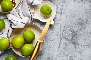 Wall Mural - Bowl with fresh ripe limes and juicer on grey background