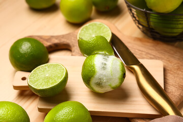 Wall Mural - Cutting board with fresh ripe limes on wooden background, closeup