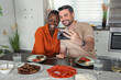 © Jelena - Interracial couple taking a selfie while having lunch in the kitchen