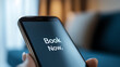 © photo for everything - Close up of mobile screen reading 'Book Now' in white letters.  Suggests booking a trip, vacation, or event; digital nomad lifestyle or online service.