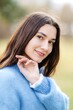 © nazariykarkhut - Young woman wearing a blue sweater is holding her chin and smiling