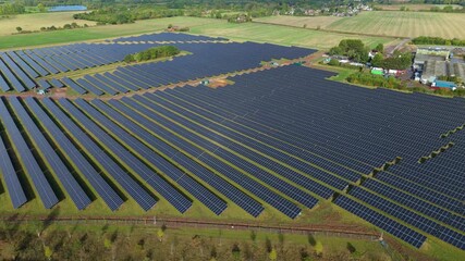 Aerial view of vast solar panel array contrasting with green fields and trees, showcasing sustainable energy in Cossington, England, United Kingdom.