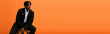 © Bliss - Stylishly dressed young man poses confidently against an orange backdrop