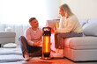 © New Africa - Couple near electric heater at home. Orange light of warmth coming out of device