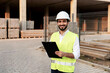 © angutyo - young man architect wearing safety vest helmet holding tablet smiling construction site Joven arquitecto con chaleco de seguridad y casco sosteniendo una tableta y sonriendo en una obra