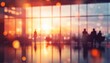 © Studicon - The image shows blurry silhouettes of people inside a building with large windows, looking out at a city sunset.