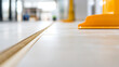 © photo for everything - Floor installation shows tiles with a natural wood expansion joint and a yellow plastic tool used for spreading adhesive or grout in a bright, modern space.