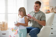 © New Africa - Father brushing his daughter's hair in armchair at home