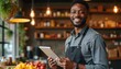 © Vadym - Black man with tablet in cafe. Smiling owner manages shop, uses tech for business. Person works in coffee house, serves customers, checks inventory. Young guy owns small cafe, happy, productive.