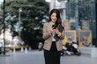 © Kritdanai - Confident Asian Businesswoman Using Smartphone Outdoors