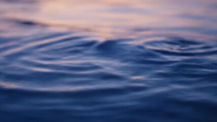 Wall Mural - Abstract patterns of water ripples on a calm surface reflect the fading light of dusk, captured with a slow macro dolly shot showcasing intricate textures stillness, orange, evening