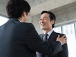 © Jumpei - スーツ姿の日本人ビジネスマン二人が笑顔で肩をたたき合い信頼関係を築くビジネスシーン
