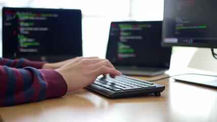 Typing on a Keyboard with Multiple Monitors Displaying Code Indoors