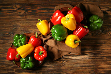 Wall Mural - Bowl and plate with fresh colorful bell peppers on wooden background