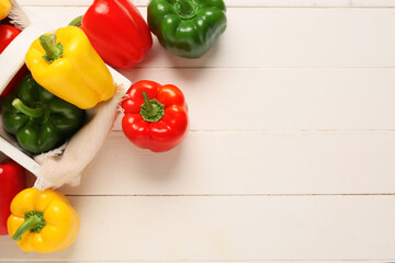 Wall Mural - Basket with fresh colorful bell peppers on white wooden background