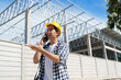 © crizzystudio - Construction worker talking on mobile phone at site