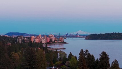 Wall Mural - A scenic twilight shot of blue seas of West Vancouver with a view of Dundarave's Skyscrapers with the Lion's Gate Bridge on the horizon.