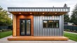 © supaporn - Accessory Dwelling Unit Modern small building featuring a mix of wood and metal, surrounded by greenery and showcasing large glass windows.