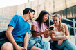 © Westend61 - Friends sharing content on smartphone and relaxing outdoors on campus