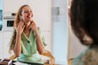 © Westend61 - Woman smiling while trying on earrings in a bright home interior