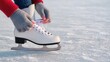 © Наталия Пилипенко - Close-up of person tying white figure skate laces on ice rink. Perfect for illustrating winter sports, skating preparation, outdoor recreation, and active lifestyle content