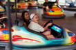 © Westend61 - Friends laughing in bumper car ride at night fair