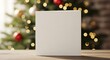 © Aman - Blank white square card on a wooden table with christmas tree and lights in background