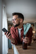 © Migma_Agency - Smiling man cleaning home checking smartphone