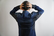 © yashis007 - Rear view of an anonymous man in a blue shirt holding his head in his hands, concept of stress, despair, burnout and mental health issues