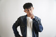 © yashis007 - Portrait of a pensive young Asian man with a hand on his chin, deeply contemplating an idea or problem against a plain white background