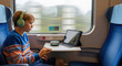 © mashimara - A Journey of Audio Delight: A young person immersed in a world of sound, enjoying a tranquil journey on a train, a portable tablet and wireless headphones bring joy to travel