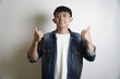 © yashis007 - Cheerful young adult man in a denim shirt expresses strong approval and success with a double thumbs-up gesture, radiating happiness and satisfaction