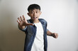 © yashis007 - Excited Asian man reaching forward in a denim jacket against a white background