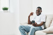 © SHOTPRIME STUDIO - Happy young African man using smartphone in bright living room, casual outfit, smiling, enjoying leisure time, modern interior, relaxed atmosphere