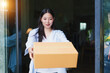 © WITTAYA  ANGMUJCHA - Woman Receiving Package at Home with Warm Smile and Bright Natural Light in Cozy Indoor Setting