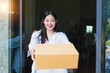 © WITTAYA  ANGMUJCHA - Young woman smiling while receiving delivery package at home, demonstrating joy and convenience of online shopping