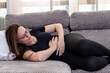 © Ivi - Powerlightss - Woman suffering from strong stomach ache lying on sofa at home