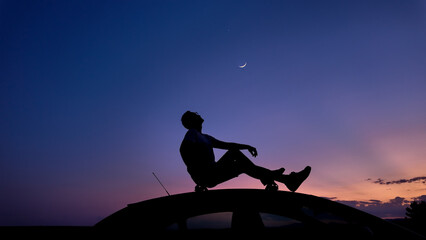 Wall Mural - Man watching stars, Milky Way, planets, Moon and other celestial objects from a car rooftop from a dark countryside location.