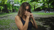 © Krakenimages.com - Woman wearing black sunglasses and a blue top with clenched fists punching air in park; empowerment.