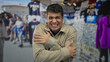 © Krakenimages.com - Man covers hands as shiver hits market, while male young hispanic visitor scans outdoor stall crowd.